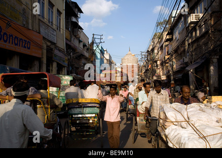 Ein Mann kämpft sich durch die verstopften Straßen von Old Delhi mit einer schweren Last auf dem Kopf, Delhi, Indien Stockfoto