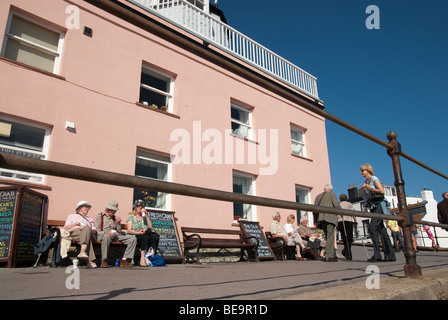 Olde Menschen saßen auf Bank außerhalb Restaurent in der Sonne Glanz bei Lyme Regis Stockfoto