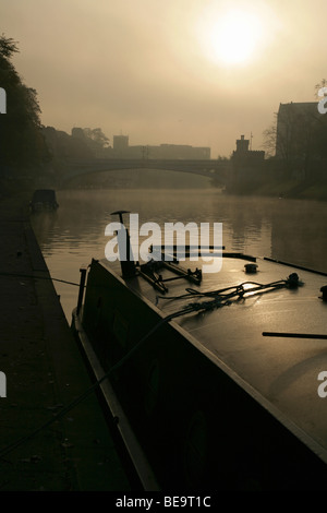 Schmale Boot vor Anker am Fluss Ouse in der Nähe von Lendal Straßenbrücke an einem nebligen Morgen, York, North Yorkshire, England. Stockfoto