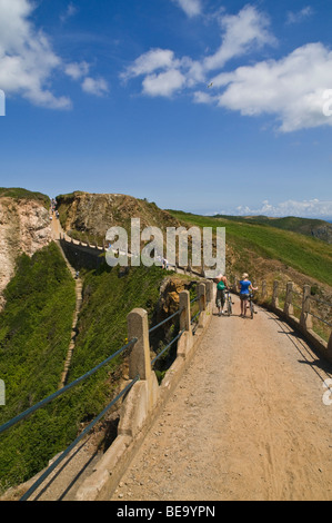 dh LA COUPEE SARK Inseltouristen und Fahrräder auf La Coupee Causeway Straße Stockfoto