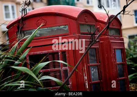 Alten altmodischen British Telecom rote Telefonzelle in einem schlechten Zustand mit Grafitti und bewachsene Umgebung, Brighton, UK. Stockfoto