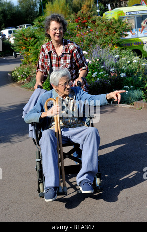 Mittlere gealterte Tochter nehmen alte Mutter im Rollstuhl für Ausflug Stockfoto
