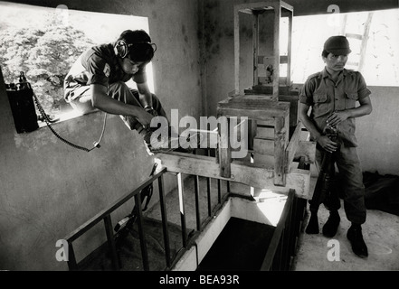 LISLIQUE DORF, LA UNION, EL SALVADOR, FEBRUAR 1982.  Die Armee Funker bindet seine Bootlace vor ihren Zug, im Glockenturm der Dorfkirche, basierend auf Patrouille.    Foto: Mike Goldwater Stockfoto