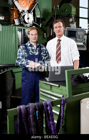 Ein Betriebsleiter und ein Fabrikarbeiter in einer Fabrik von Metallteilen Stockfoto