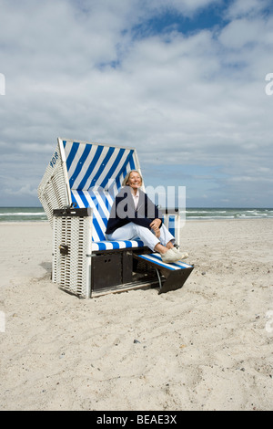 Ein senior Frau sitzt im Strandkorb mit Kapuze Stockfoto