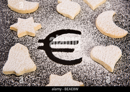 Das Euro-Symbol in Puderzucker, umgeben von verschiedenen geformten cookies Stockfoto