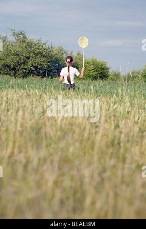 Rückansicht eines jungen Mädchens fangen Schmetterlinge in einem Feld Stockfoto