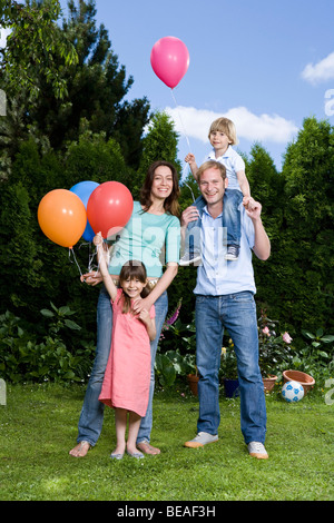 Zwei Eltern und ihren beiden Kindern Luftballons, im Freien halten Stockfoto