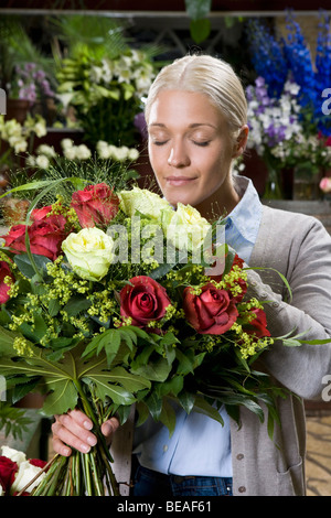 Eine Frau einen Blumenstrauß in einem Floristen riechen Stockfoto