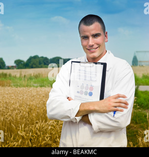 Landwirtschaft-Wissenschaftler, die Notizen auf dem Gebiet mit Gewächshäusern im Hintergrund Stockfoto