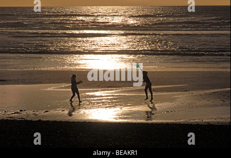 Silhouette junge Frauen am Strand mit einer Frisbee spielen in Greymouth auf der neuseeländischen Südinsel. Tasmanische See Stockfoto