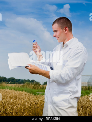 Landwirtschaft-Wissenschaftler, die Notizen auf dem Gebiet mit Gewächshäusern im Hintergrund Stockfoto