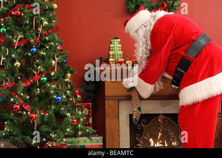 Santa Claus Weihnachtsgeschenke in Strümpfen setzen Stockfoto