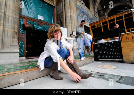 Ein westlicher Besucher in eine türkische Moschee entfernen ihre Schuhe vor dem Betreten des muslimischen Ort der Anbetung. Stockfoto