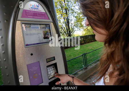 Ein französisches Mädchen, die mit dem öffentlichen Terminal 'Velib' Fahrrad mieten in Zentral-Paris, Frankreich Stockfoto