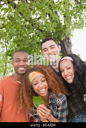 Freunde halten Blatt unter Baum Stockfoto
