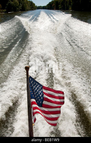 Vom Wind verwehten US-Flagge in Motorboote wecken. Stockfoto