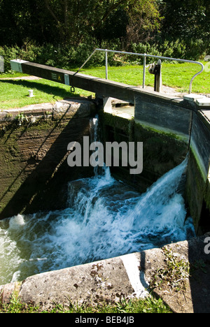 Wasser sprudelt durch geschlossene Tore der Schleuse 64 auf dem Kennet und Avon Kanal mit Cimm Marker Zeichen Stockfoto