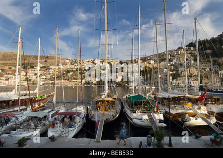 Yachten im Hafen von Yialos auf der griechischen Dodekanes Insel Symi mit den Neo-klassizistischen Häusern der Stadt im Hintergrund. Stockfoto