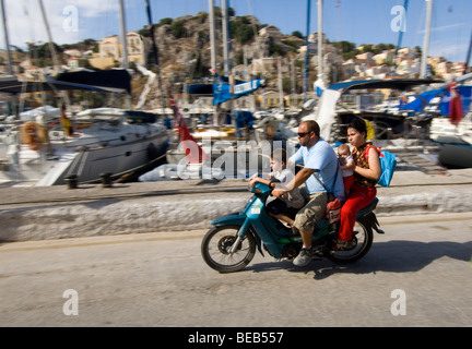 Vier Personen auf einem winzigen Moped. Eine griechische Familie reisen auf einem Motorrad ohne Helm. Stockfoto