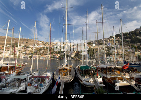 Yachten im Hafen von Yialos auf der griechischen Dodekanes Insel Symi mit den Neo-klassizistischen Häusern der Stadt im Hintergrund. Stockfoto