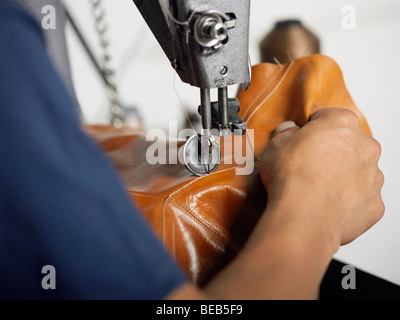 Die Hand einer Person mit einer Nähmaschine in einer Schuhfabrik in Nahaufnahme Stockfoto