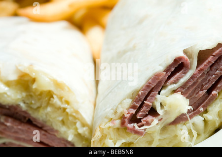 dicken Mais Rindfleisch Reuben Wrap Sandwich mit Schweizer Käse Sauerkraut und Kartoffeln Pommes frites Stockfoto