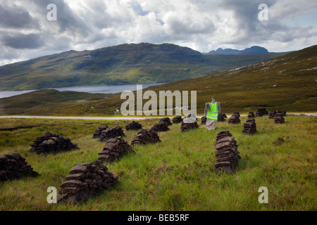 Schottische traditionelle Torfschnitt für Brennstoff & Trocknung im Hochland. Torf Stacks, & Torfböden Bodenbearbeitung in Sutherland, Schottland, Großbritannien Stockfoto