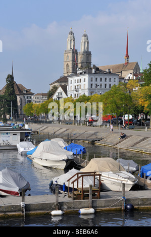 Die zwei Türme der das Grossmünster in Zürich steigen über Sportboote vor Anker an der Limmat. Stockfoto