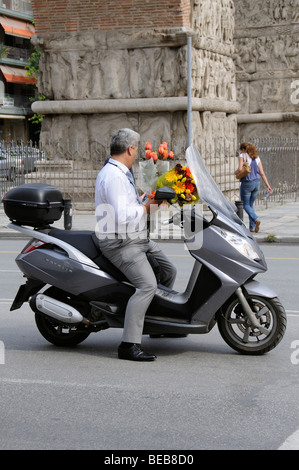 Griechischen Mann reitet einen Motorroller tragen Blumen und mit einer Handy-zentrale Thessaloniki Griechenland Stockfoto