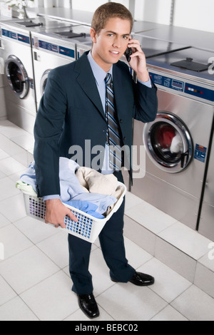 Telefonieren mit einem Handy in einem Waschsalon Geschäftsmann Stockfoto