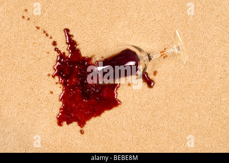 Ein Glas verschüttete Wein auf neue Teppich wird einen Fleck hinterlassen. Stockfoto