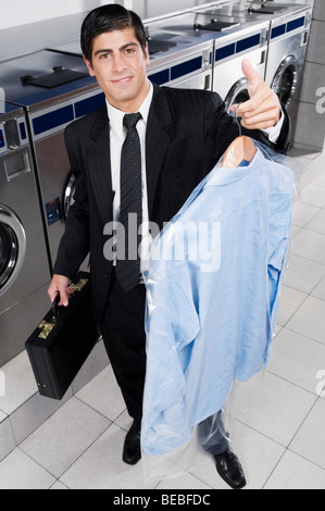 Geschäftsmann mit einem Kleiderbügel in einem Waschsalon Stockfoto