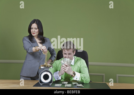 Geschäftsmann hält Geldscheine und eine Geschäftsfrau mit einem Gewicht von gold-Schmuck Stockfoto