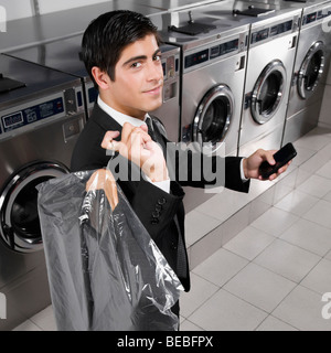Geschäftsmann SMS auf ein Handy in einem Waschsalon Stockfoto