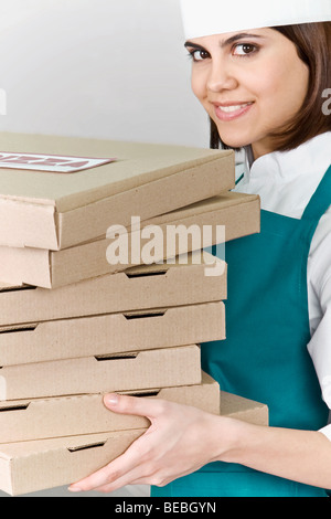 Köchin holding Stack des Pizza-Kartons und lächelnd Stockfoto