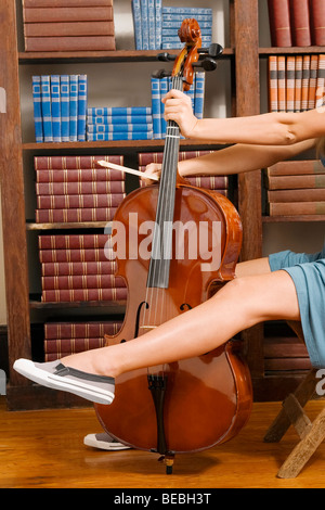 Frau spielt ein Cello in einer Bibliothek Stockfoto