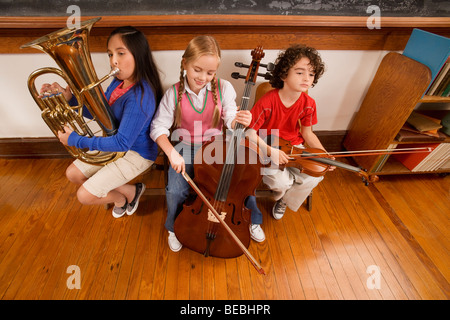 Drei Studenten spielen Musikinstrumente in einem Klassenzimmer Stockfoto