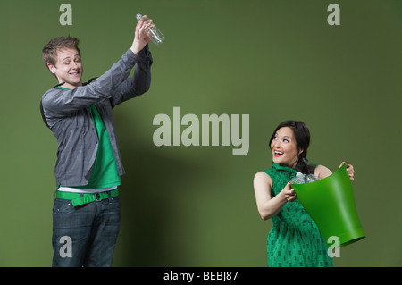 Frau hält ein Papierkorb und ein Mann wirft eine leere Wasserflasche Stockfoto