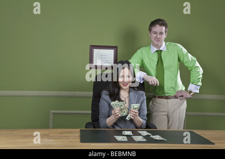 Geschäftsfrau, die Geldscheine mit einem Geschäftsmann, der neben ihr Stand halten Stockfoto
