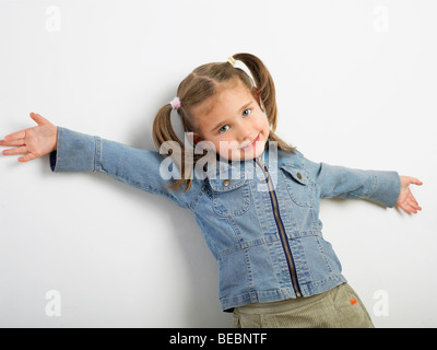 Porträt eines Mädchens stehend gegen eine Wand und lächelnd Stockfoto