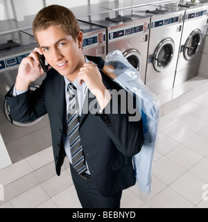 Telefonieren mit einem Handy in einem Waschsalon Geschäftsmann Stockfoto