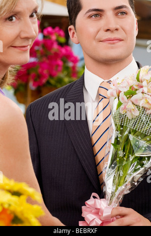Weibliche Floristen geben einen Blumenstrauß an einem Kunden Stockfoto