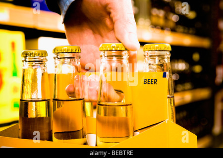 Verkäuferin trägt oben eine Kiste Bierflaschen Stockfoto