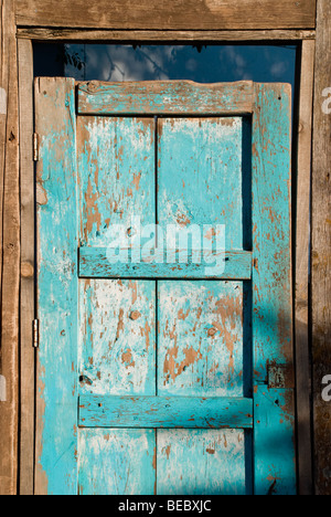 Die Abendsonne wirft Schatten auf eine bunte alte Holztür in Lincoln, New Mexico. Stockfoto