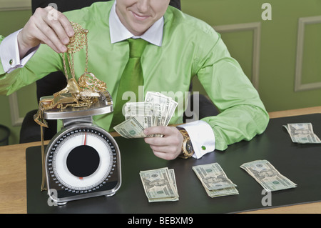 Geschäftsmann hält Banknoten und einem Gewicht von gold-Schmuck Stockfoto