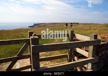 Zwei Rucksack-Wanderer passieren ein küssen Tor entlang der Cornish, den Küstenweg in der Nähe von Bedruthen in Cornwall Schritte Stockfoto