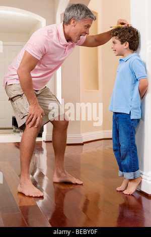 Mann, die Messung der Höhe seines Sohnes Stockfoto