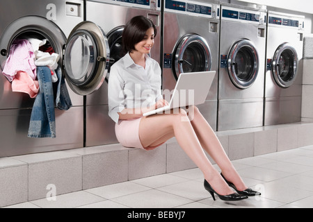 Frau mit einem Laptop in einem Waschsalon Stockfoto