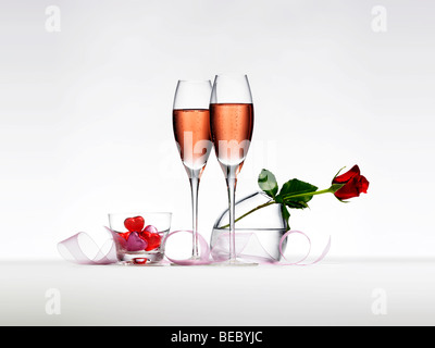 Champagner, eine rote Rose, Band und Pralinen. Stockfoto